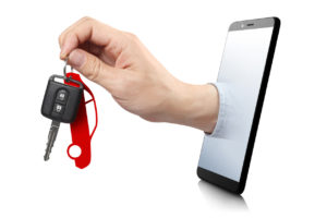 Hand reaching through a smartphone holding car keys