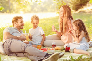 Happy young family enjoying spring summer picnic in nature
