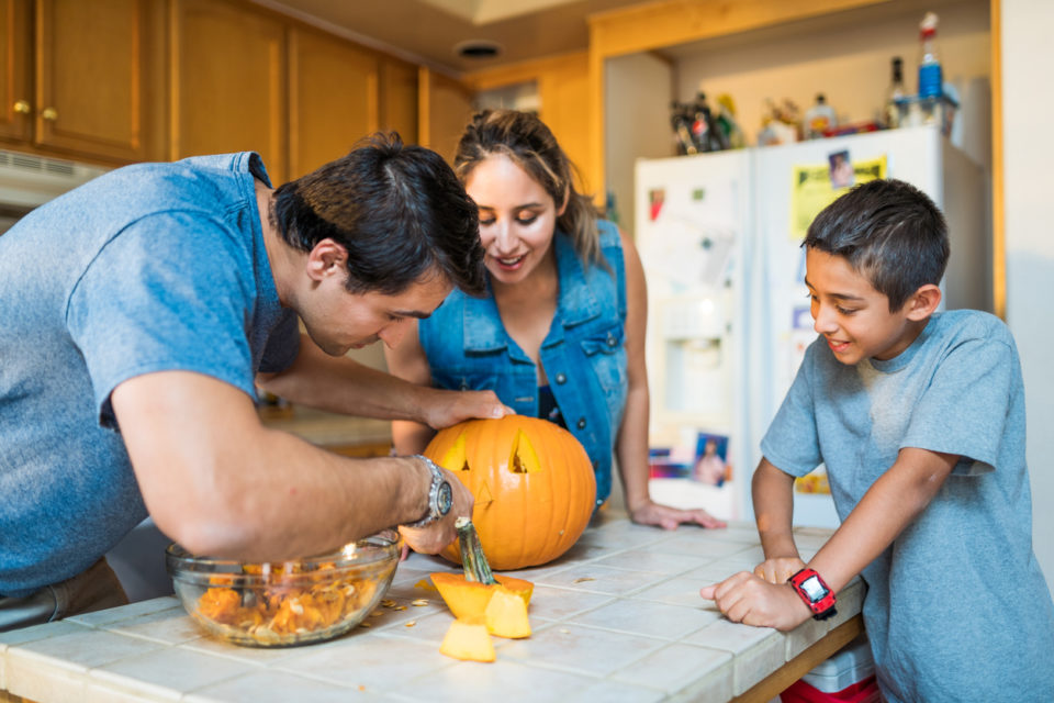 Family carving pumpkin together. Mother, Father and Son