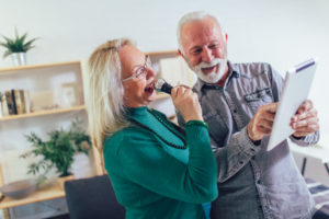 Senior couple singing karaoke at home, having fun.