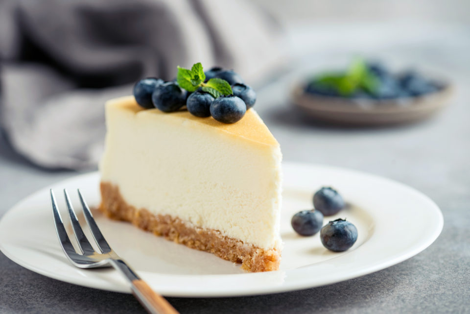 Cheesecake with blueberries on white plate.