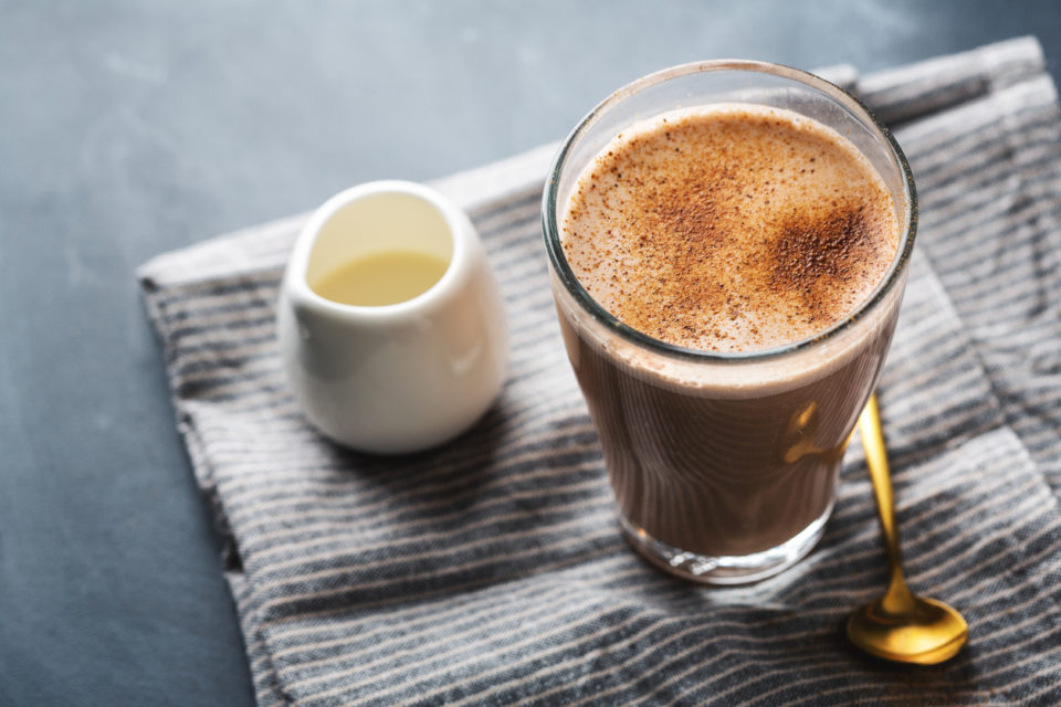 Tasty chai latte in glass on dark background.