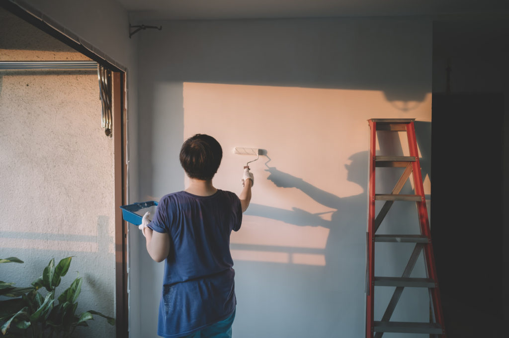Adult female painting her living room.
