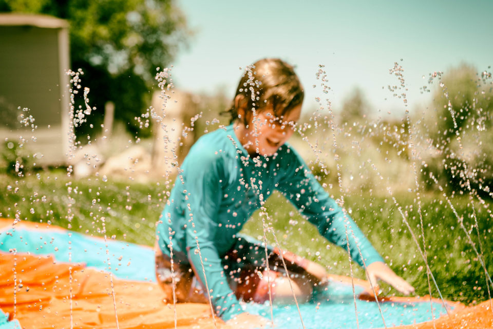 Child stays cool in a heat wave by playing on slip and slide