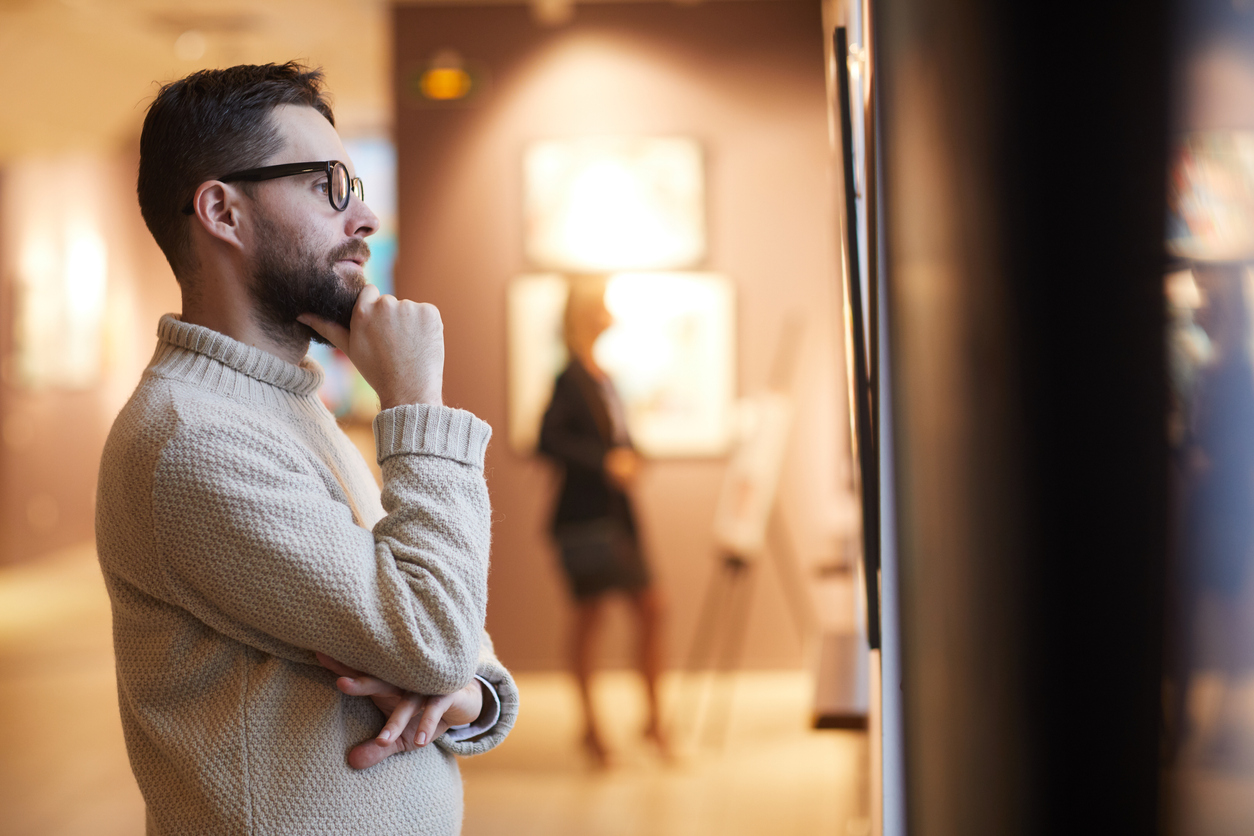 Bearded Man Looking at Paintings in Art Gallery