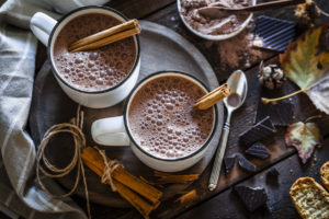 Two homemade hot chocolate mugs on rustic wooden table