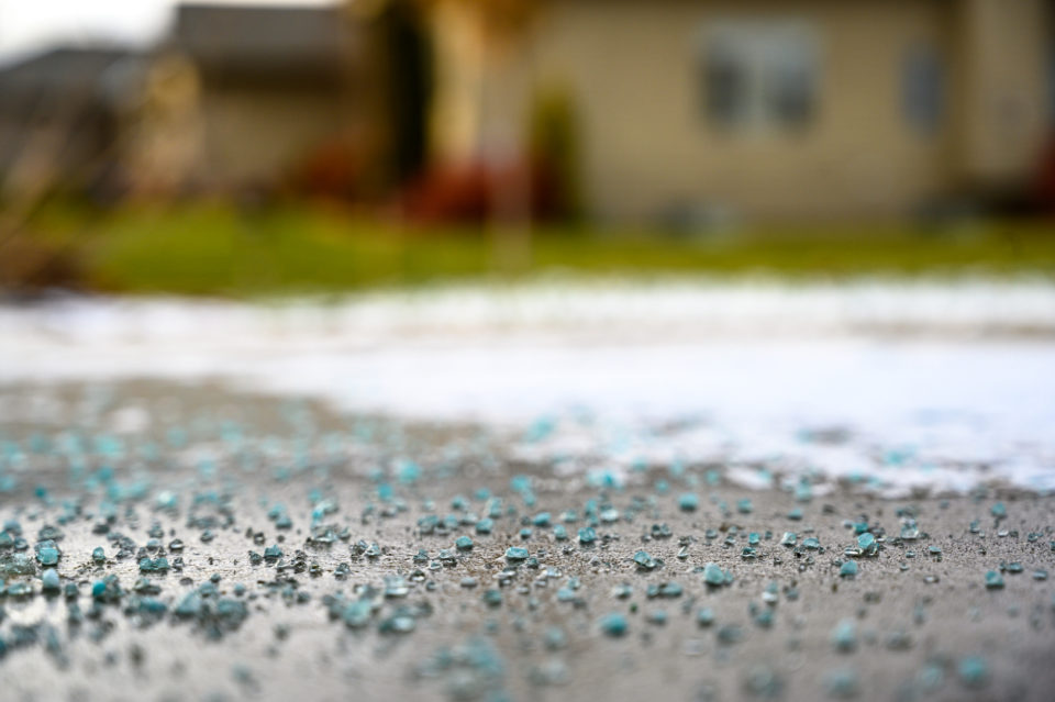 Ground level closeup view of rock salt ice-melt on concrete with snow