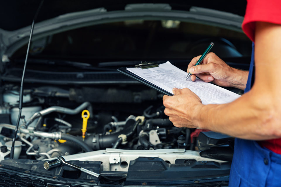 mechanic writing checklist paper on clipboard