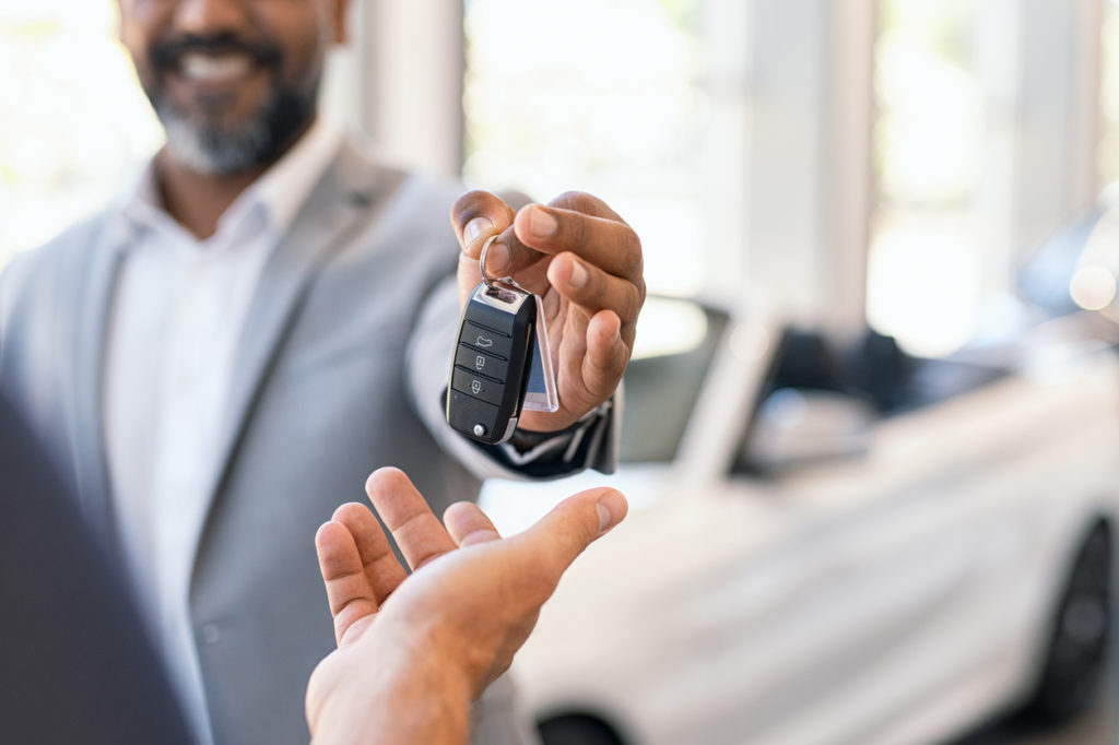 Closeup hand of car dealer giving new car key to customer.