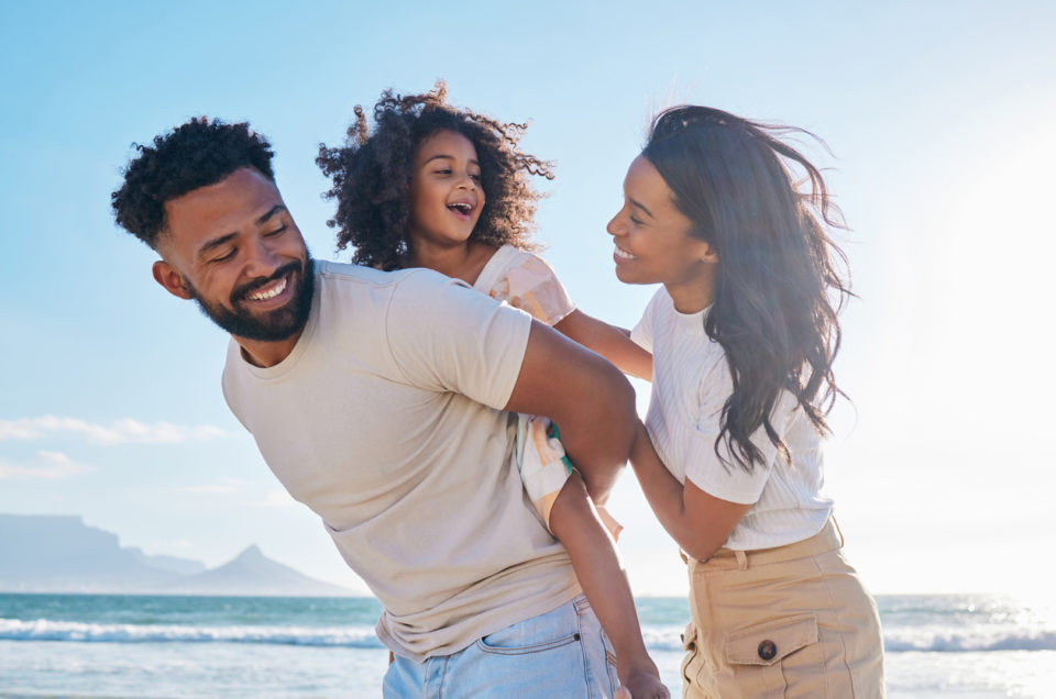 Father, mother and daughter playing on the beach