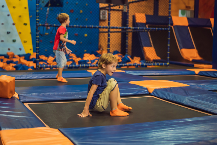 Cute boy jumping on trampoline in entertainment center.